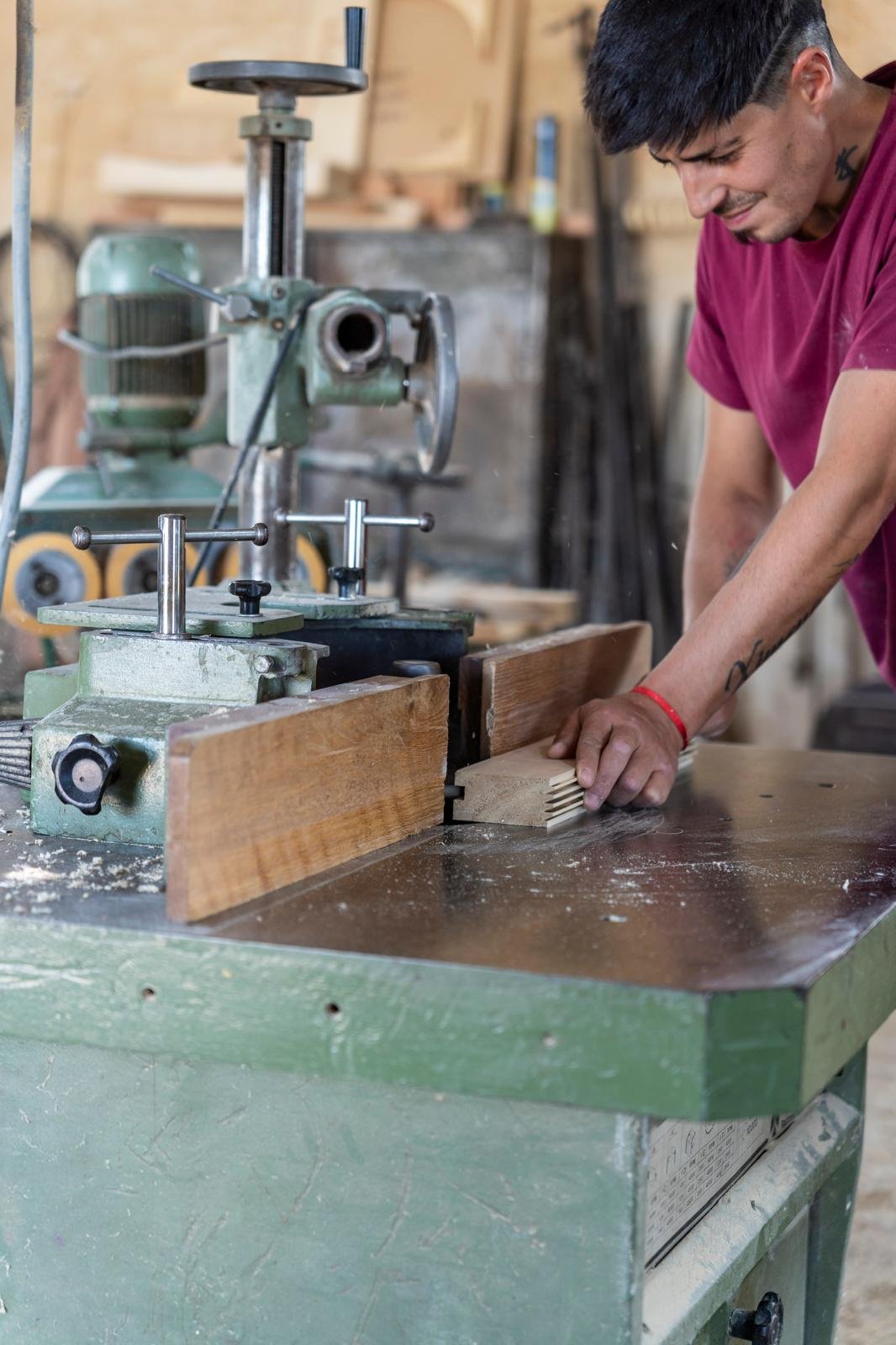 detalle en primer plano del fresado tipo finger en el canto de dos tablones de álamo macizo antes del encolado, con la unión abierta y los dientes del fresado visibles, luz artificial de taller